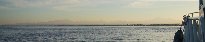 Foto taget från en båt över Röda havet med Hurghada och bergen bakom i horisonten.